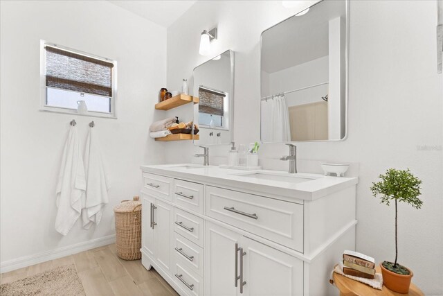 bathroom with double vanity, curtained shower, baseboards, and a sink