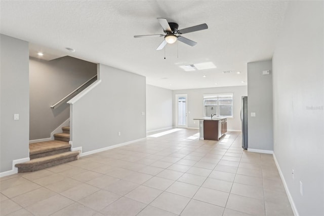6013 Blue Lily Way, Winter Garden, FL 34787 - unfurnished living room featuring ceiling fan, stairway, light tile patterned flooring, and a textured ceiling