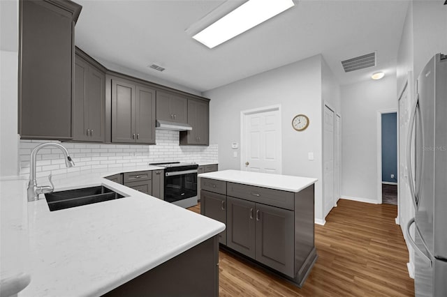 1868 Rachels Ridge Loop Unit L, Ocoee, FL 34761 - kitchen with appliances with stainless steel finishes, a kitchen island, decorative backsplash, light countertops, and wood finished floors