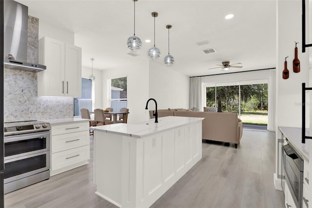kitchen with wall chimney range hood, visible vents, tasteful backsplash, appliances with stainless steel finishes, and ceiling fan