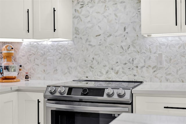kitchen featuring stainless steel range with electric cooktop, backsplash, white cabinetry, wallpapered walls, and light countertops