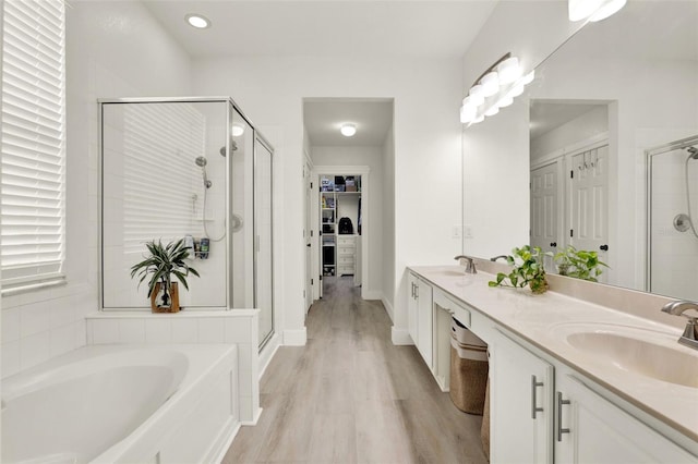 full bathroom with a shower stall, a bath, a sink, and double vanity