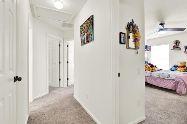 corridor with attic access, carpet floors, visible vents, and baseboards