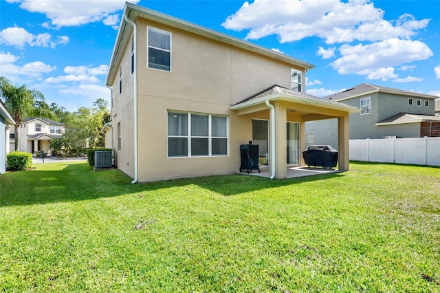 back of property with central air condition unit, fence, a patio area, a yard, and stucco siding