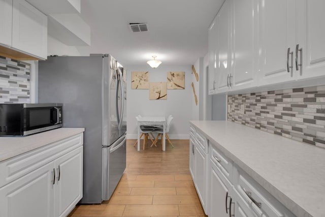 6464 Inca St, Orlando, FL 32807 - kitchen featuring stainless steel microwave, light countertops, white cabinets, and backsplash