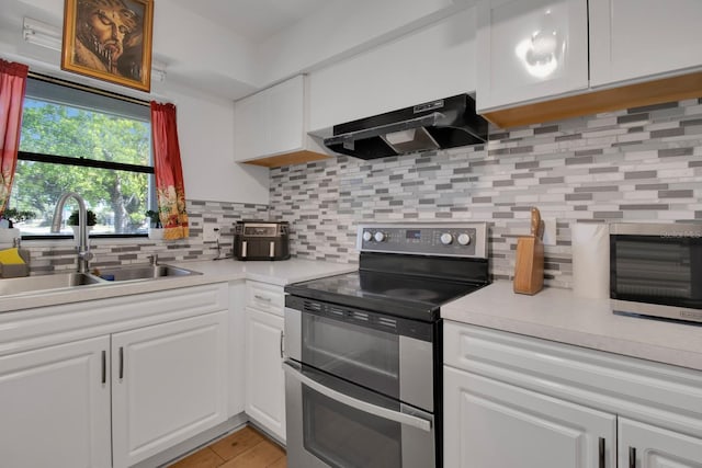 6464 Inca St, Orlando, FL 32807 - kitchen featuring range with two ovens, under cabinet range hood, a sink, light countertops, and white cabinets