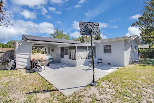 6464 Inca St, Orlando, FL 32807 - back of house featuring a sunroom, a patio area, roof mounted solar panels, and concrete block siding