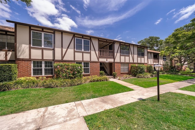 view of front of property with stucco siding, a front yard, and brick siding