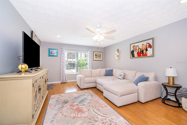 living area with baseboards, light wood-type flooring, and a ceiling fan