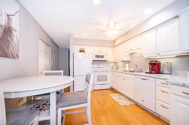 kitchen featuring a sink, a ceiling fan, light wood-style flooring, white appliances, and white cabinets