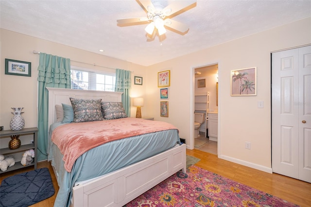 bedroom with baseboards, light wood-type flooring, ceiling fan, and ensuite bathroom