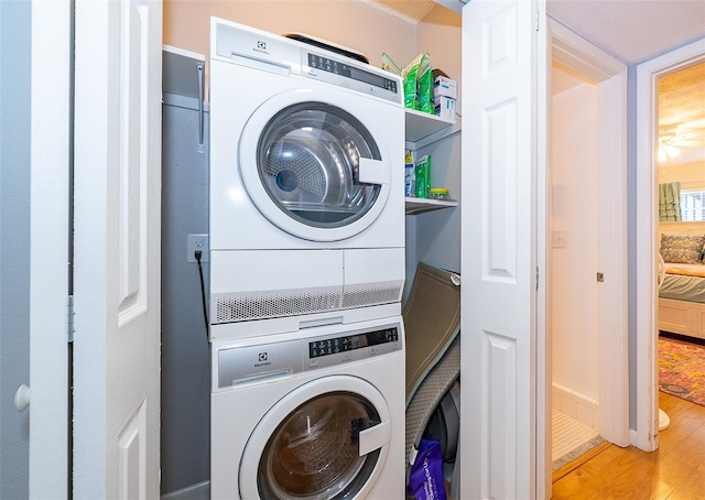 laundry area featuring wood finished floors, stacked washing maching and dryer, and laundry area