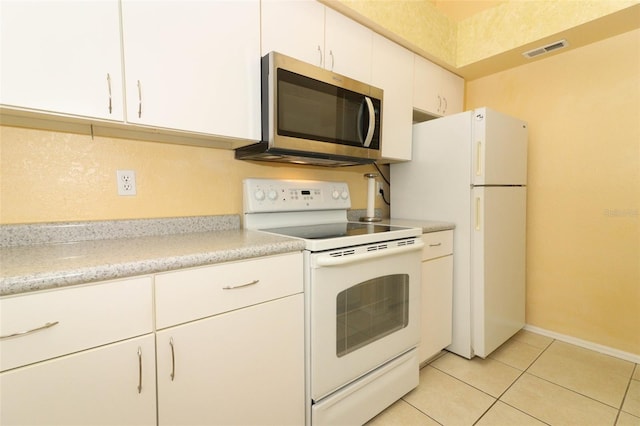 kitchen with light tile patterned floors, white appliances, visible vents, light countertops, and white cabinets