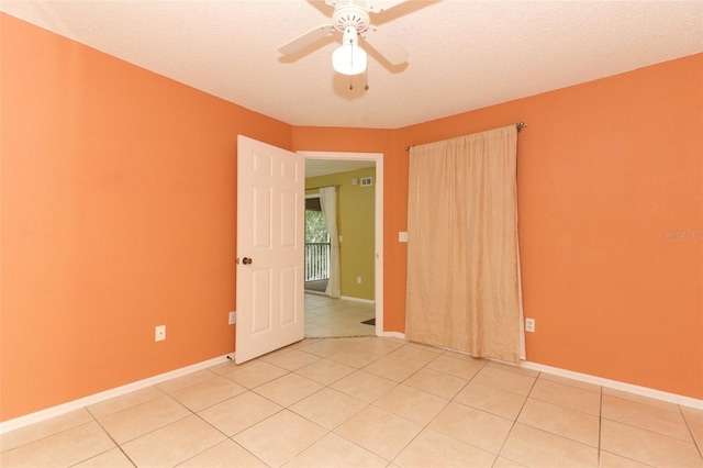 empty room with light tile patterned flooring, ceiling fan, a textured ceiling, and baseboards