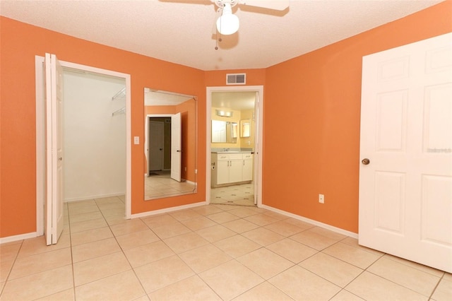unfurnished bedroom with light tile patterned floors, visible vents, a walk in closet, and a closet