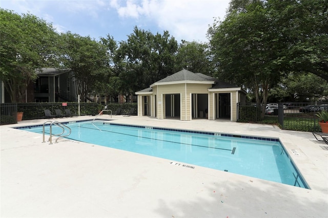 community pool with a patio area and fence