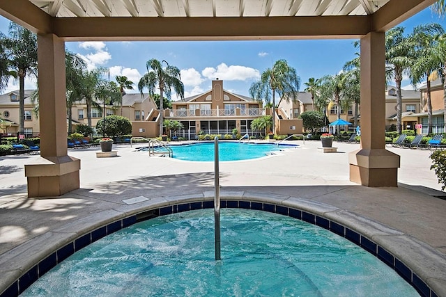 community pool featuring a patio, a residential view, and a hot tub