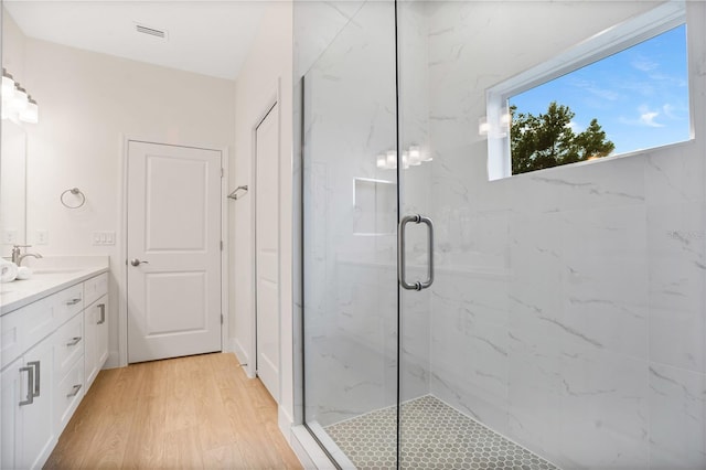 full bath with visible vents, wood finished floors, a marble finish shower, and vanity