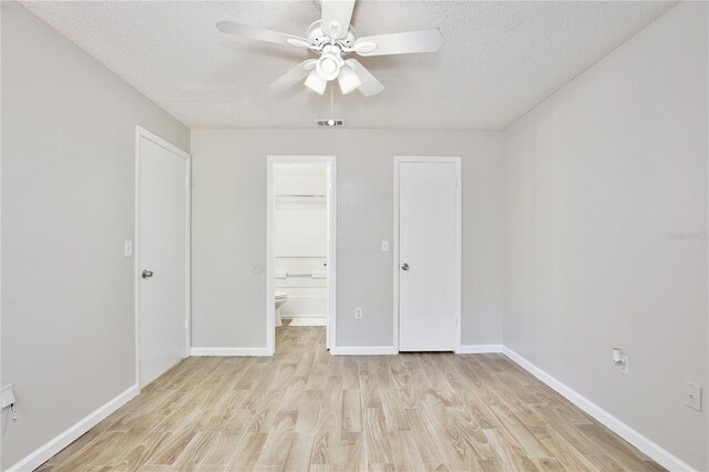 956 Salt Pond Pl Unit 207, Altamonte Springs, FL 32714 - unfurnished bedroom with light wood finished floors, a textured ceiling, baseboards, ensuite bath, and a ceiling fan
