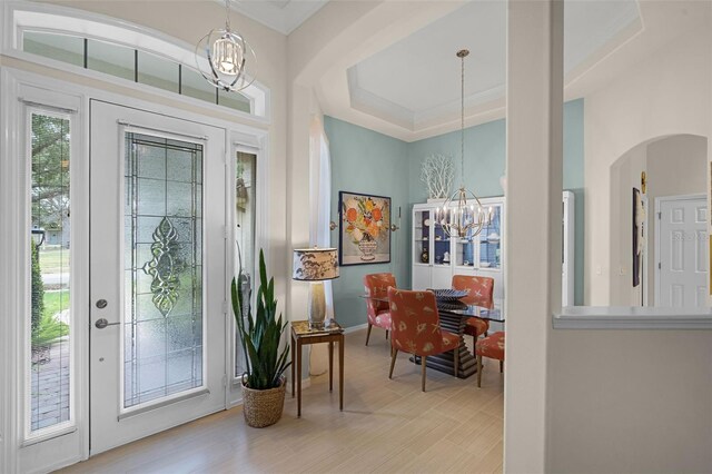 foyer featuring baseboards, arched walkways, and a notable chandelier