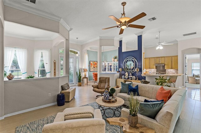 living area with arched walkways, a ceiling fan, and visible vents