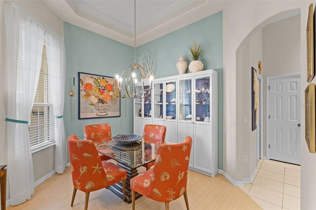 tiled dining room featuring arched walkways, crown molding, a chandelier, and baseboards