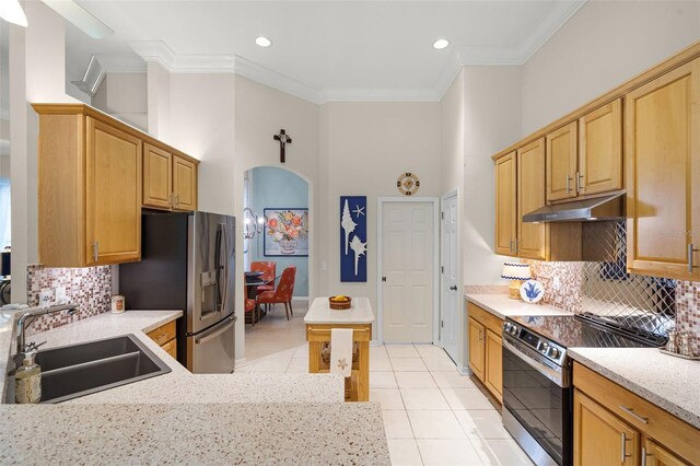 kitchen with a sink, light tile patterned flooring, a towering ceiling, stainless steel appliances, and under cabinet range hood