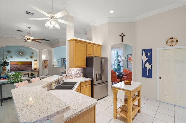 kitchen with ceiling fan, a sink, arched walkways, and stainless steel fridge