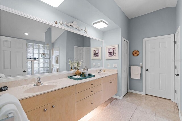 bathroom featuring double vanity, tile patterned flooring, baseboards, and a sink