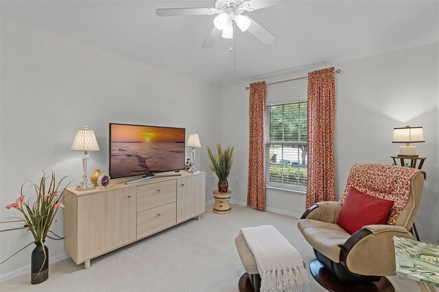sitting room featuring a ceiling fan, baseboards, and light carpet