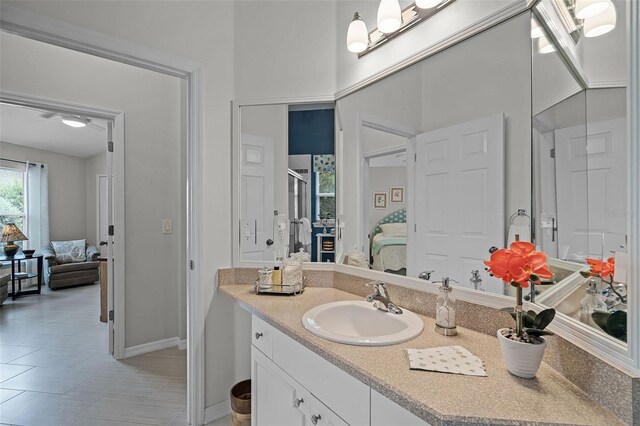 ensuite bathroom with connected bathroom, baseboards, vanity, and tile patterned floors