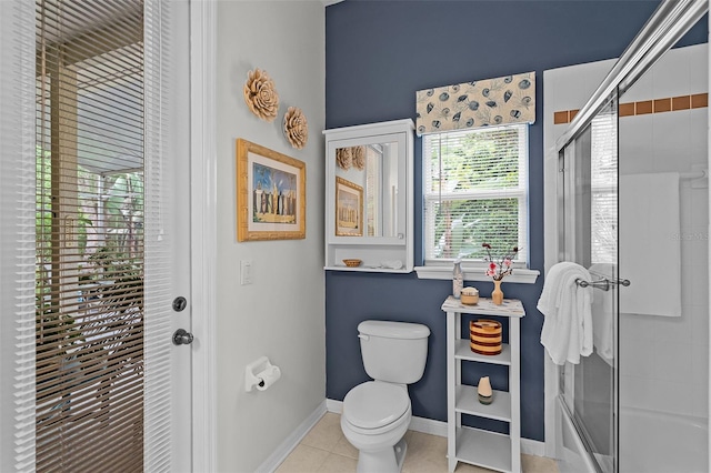 bathroom featuring a tile shower, toilet, tile patterned flooring, and baseboards