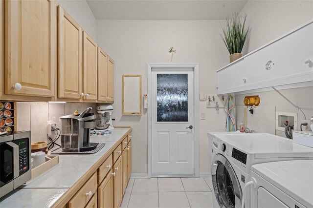 clothes washing area featuring washing machine and dryer, baseboards, and light tile patterned flooring