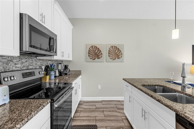 9025 Dogleg Dr, Davenport, FL 33896 - kitchen with white cabinets, stainless steel appliances, baseboards, and dark stone counters