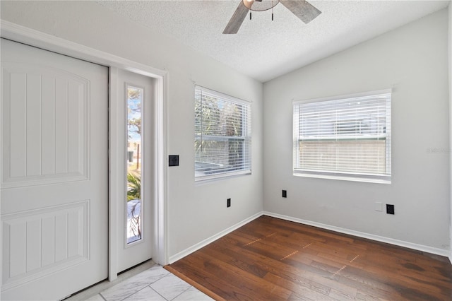 foyer featuring lofted ceiling, a ceiling fan, baseboards, a textured ceiling, and wood finished floors