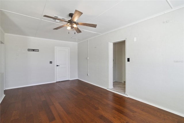 spare room with wood finished floors, attic access, baseboards, a ceiling fan, and crown molding