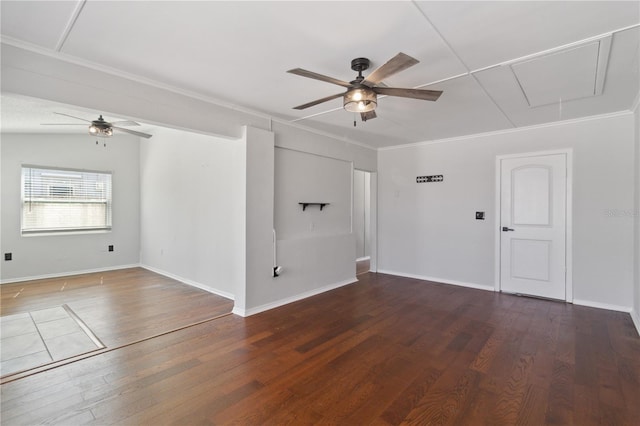 empty room featuring attic access, wood finished floors, a ceiling fan, and crown molding