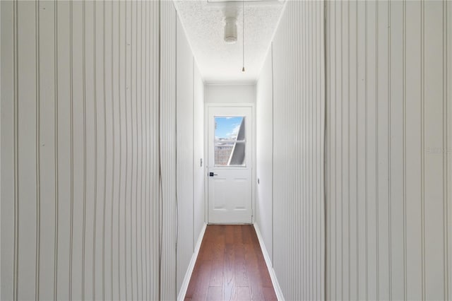 corridor with dark wood finished floors, baseboards, attic access, and a textured ceiling