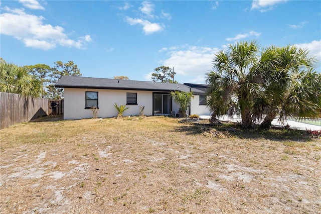 rear view of house featuring fence and stucco siding