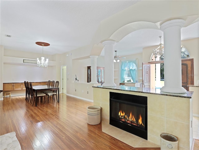 4675 Ficus Dr, Beverly Hills, FL 34465 - living room with light wood-style flooring, visible vents, baseboards, a tile fireplace, and decorative columns