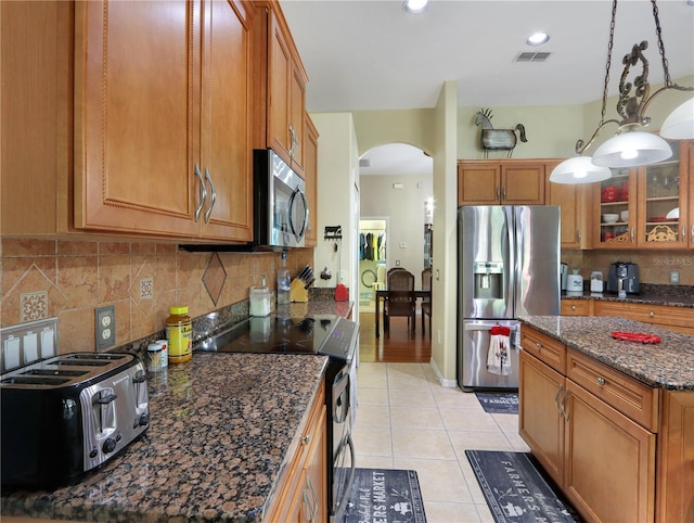 4675 Ficus Dr, Beverly Hills, FL 34465 - kitchen with tasteful backsplash, appliances with stainless steel finishes, visible vents, arched walkways, and brown cabinetry
