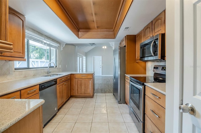 121 Primrose Dr, Longwood, FL 32779 - kitchen featuring stainless steel appliances, a tray ceiling, a peninsula, a sink, and light tile patterned floors