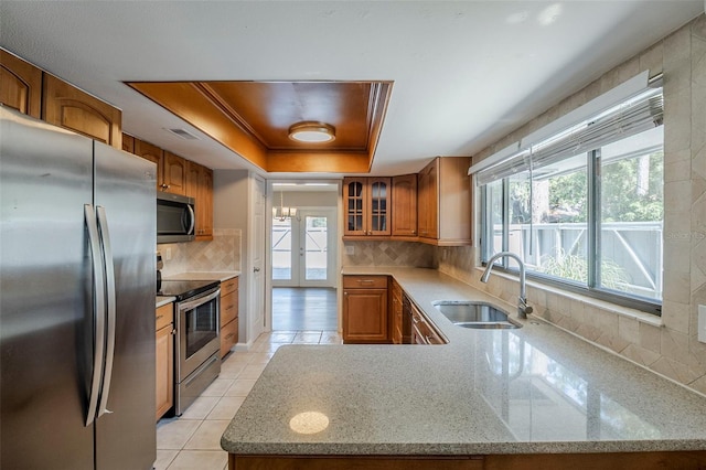 121 Primrose Dr, Longwood, FL 32779 - kitchen featuring appliances with stainless steel finishes, a sink, brown cabinetry, a raised ceiling, and tasteful backsplash