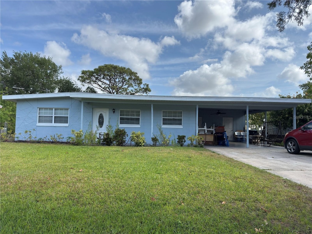 ranch-style house with a front yard, ceiling fan, an attached carport, and concrete driveway