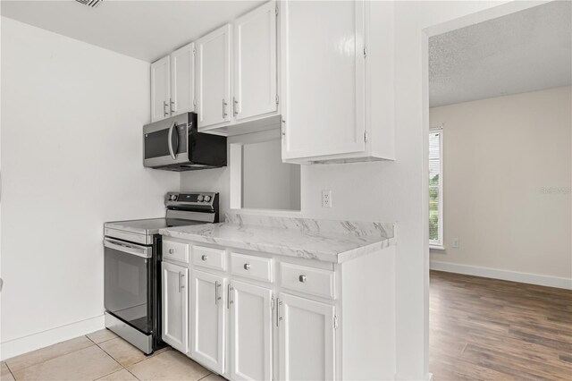 4038 Versailles Dr Unit 4038C, Orlando, FL 32808 - kitchen with white cabinets, baseboards, and appliances with stainless steel finishes