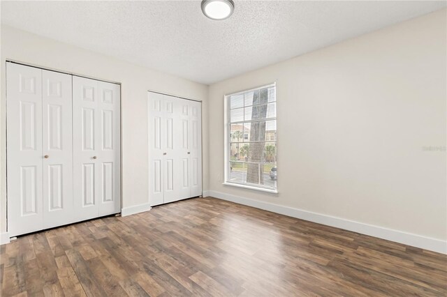 4038 Versailles Dr Unit 4038C, Orlando, FL 32808 - unfurnished bedroom featuring baseboards, multiple closets, wood finished floors, and a textured ceiling
