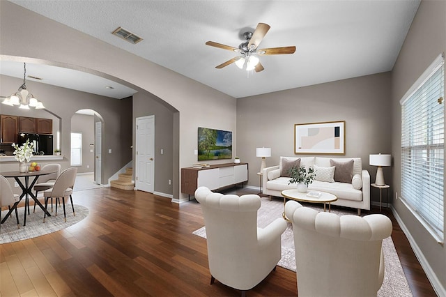 16064 Old Ash Loop, Orlando, FL 32828 - living room featuring visible vents, dark wood-style flooring, baseboards, arched walkways, and ceiling fan with notable chandelier