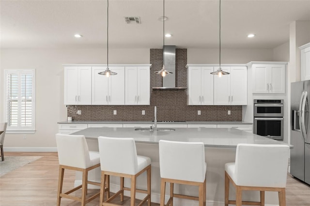 8017 Chilton Dr, Orlando, FL 32836 - kitchen featuring wall chimney exhaust hood, appliances with stainless steel finishes, decorative backsplash, light wood finished floors, and recessed lighting