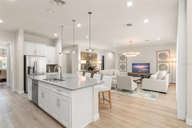 8017 Chilton Dr, Orlando, FL 32836 - kitchen featuring a sink, open floor plan, white cabinetry, an island with sink, and light wood-style floors