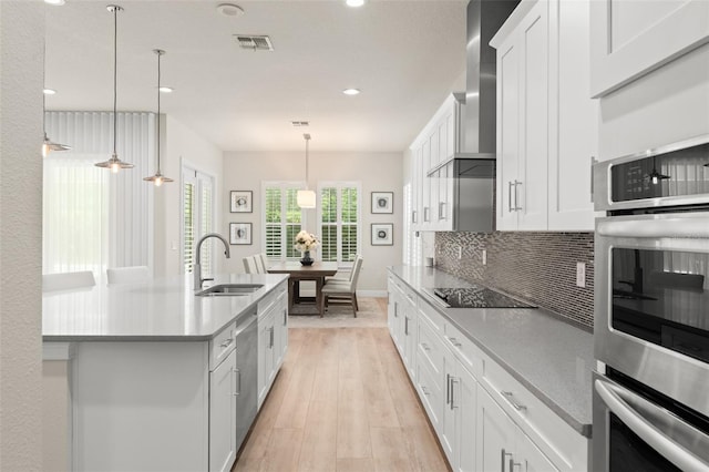 8017 Chilton Dr, Orlando, FL 32836 - kitchen featuring a sink, black electric cooktop, stainless steel dishwasher, light wood-type flooring, and wall chimney exhaust hood